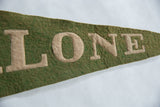 Hand-sewn beige block letters 'ONE' on a vintage green wool felt pennant.