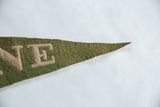 Textured green felt banner close-up, showing pointed end and beige hand-sewn NE letters.