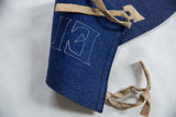 Vintage Elmira felt pennant detail: blue felt, white stitched 'E' letter, and beige ties.