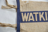 Aged beige felt pennant with hand-sewn 'WATKI' letters, blue stripe, and side tie.