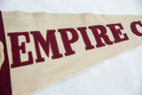 Angled view showing the felt texture and stitched burgundy letters on the Empire pennant.