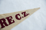 Angled view of the stitched maroon letters on the tapered end of the tan felt flag.