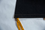 Vintage black felt pennant's corner with yellow ties and golden stitching.