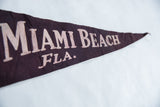 Detail of vintage felt pennant with 'Miami Beach Fla.' text and visible creasing.