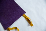 Deep purple felt flag corner with red stitching and mustard yellow tie.
