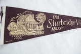 Detailed view of the Old Sturbridge Village felt pennant's cottage and water wheel graphic.