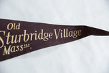 Cream-colored serif text for Old Sturbridge Village on a dark brown vintage felt pennant.