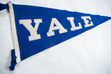 Close-up of vintage Yale felt pennant, showing white YALE letters and blue felt texture.