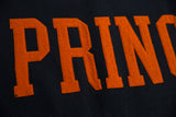 Detail of orange felt 'PRINC' letters with visible stitching on a black vintage banner.