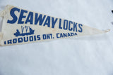 The blue lettering, ship graphic, and aged texture on the vintage felt pennant.