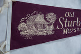 Detailed cottage and water wheel graphic on the burgundy felt Old Sturbridge Village flag.
