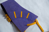 Purple felt texture with yellow appliqued strips and orange edge stitching on vintage banner.