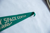 Curved tip of vintage green felt Kennedy Space Center pennant with cream lettering.