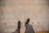 Distressed vintage Oushak rug with rose field, pale grey vine motifs, and colorful banded borders.