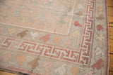 Distressed Oushak rug corner, pale rose field, geometric and pastel blossom borders.