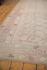 Detail of vintage distressed Oushak carpet: faded rose field, silver tree of life vinery, red geometric border.