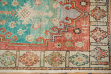 Distressed Oushak runner corner, showing worn turquoise, soft red, and ivory floral border.