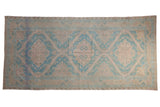 A distressed vintage Soumac runner with triple geometric medallions in pale denim blue, mauve, and beige.
