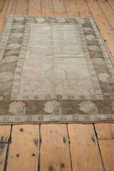 Vintage distressed Oushak rug: ivory field with faded powder blue shadow medallions and coffee floral border.