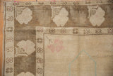 Worn knot heads and muted blossom patterns on a distressed vintage Oushak rug corner.