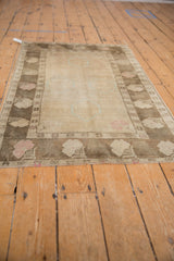 Angled view of the vintage Oushak rug's softly worn pile and faded floral border.