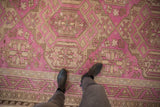 A scale view of a distressed fuchsia and sand Soumac carpet with geometric starburst floral designs.