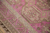 Close-up of the vintage Soumac's serrated border and starburst floral in fuchsia and sand.