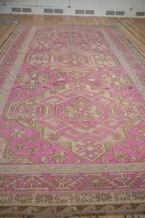 Long perspective view of a vintage fuchsia and ivory Soumac carpet showing repeating medallions.