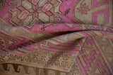 Soft folds of a vintage Soumac carpet showing its woven texture and fuchsia geometric details.