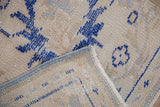 Vintage Oushak rug corner reveals blue side cord and woven foundation.