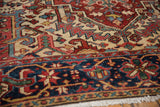 Vintage Heriz rug: navy blue border and ivory field with geometric vinery, visible wear.