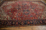 Vintage Heriz carpet's navy trefoil and floral main border, brick red field, green accents.