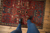 Red vintage Northwest Persian rug with central medallion, Herati fish boteh, and feet.