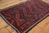 Antique Belouch rug corner: latch-hooked palmettes, bold vine border, goat hair selvage.