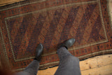 Vintage Belouch rug with repeating geometric guls and pawn motif borders, showing wear.