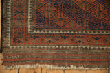 Vintage Belouch rug corner with geometric patterns, ivory reciprocating pawn border, and tattered fringe.