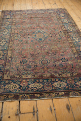 Angled view of vintage Yezd rug's cochineal red floral field and Farsi inscribed border.