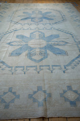 Worn pile texture on a distressed vintage Oushak rug, pale denim blue geometric border.