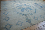 Vintage distressed Oushak rug with faded blue stepped gul border and ivory field.