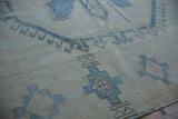 Distressed Oushak carpet texture with worn ivory pile and pale denim blue stepped guls.
