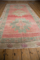 Angled view of vintage distressed Oushak runner with triple dusty blush and oxidized silver medallions.