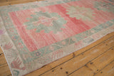 Distressed Oushak runner showing dusty blush field, time-softened pile, and meandering vine borders.