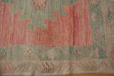 Close-up of distressed vintage Oushak rug with pink field and oxidized silver finned border.