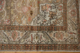 Close-up of distressed vintage Kaisary rug border, showcasing geometric starbursts and scrolling floral patterns in dusty blush and coffee brown.