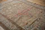 Distressed field with scrolling vines and geometric main border in dusty blush, bronze, and ivory.