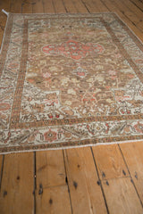 Distressed Kaisary rug, geometric starburst border and scrolling vines in dusty bronze, blush, ivory.