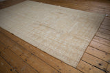 Corner view of the distressed Oushak rug, highlighting its geometric pawn and trefoil border.