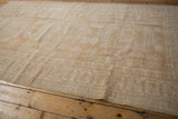 Distressed Oushak rug with decorative reciprocating pawn motif outer border.