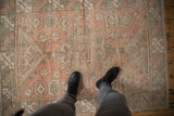Vintage distressed Melas rug featuring geometric guls and starbursts in muted rose, green, and ivory.