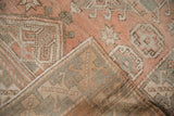 Corner view of distressed Melas rug, revealing geometric pile in dusty rose and woven foundation.